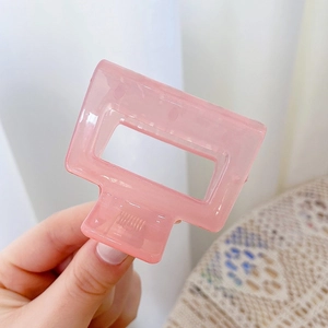 Detail view of a pink rectangular frosted hair claw clip with a hollow design