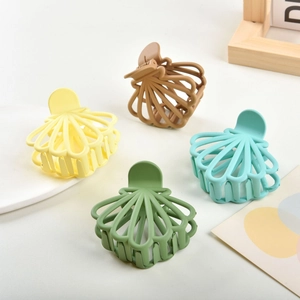 Set of four colorful shell-shaped hair claws in matte yellow, brown, and green tones