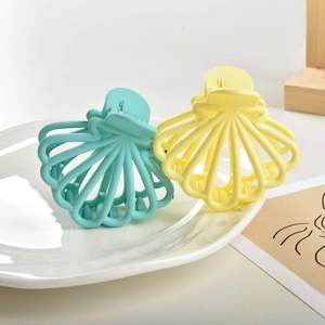 Detail of shell shaped matte hair claws in tiffany green and pale yellow colors