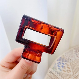 Detail of a square amber tortoiseshell hair claw clip made of acrylic material
