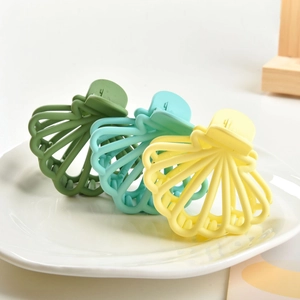 Three-piece matte finish shell hair claws in green, blue, and yellow on a ceramic tray