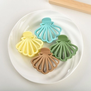 Close-up of four matte shell hair claws in pastel colors on a white ceramic plate