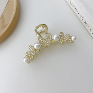 Detalle de la elegante pinza para el pelo dorada con perlas grandes y corazones