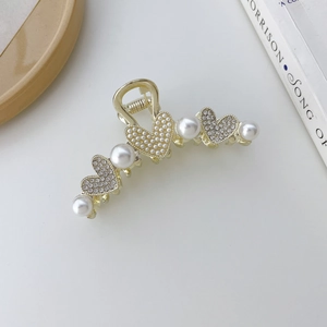 Detalle de la pinza para el cabello de corazón dorado con perlas y strass brillante