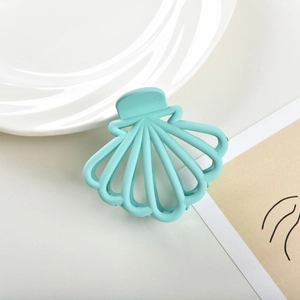 Detailed view of a mint green shell-shaped hair claw clip with a matte finish