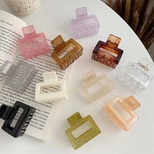 Square resin hair claw clips set in multi-colors shown on white table with book