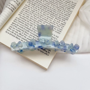Detail view of large marble blue floral claw clip on a book with rhinestone centers