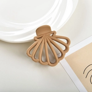 Close-up of shell-shaped matte hair claw clip in soft brown with hollow design