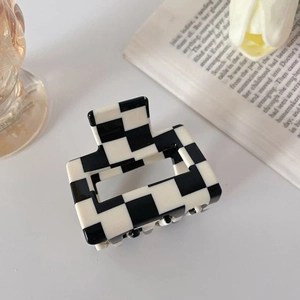 Detail shot of checkered hair claw clip with vintage aesthetic on a minimalist background