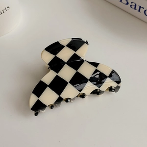 Detail of checkered hair claw clip with vintage black and white pattern on white background