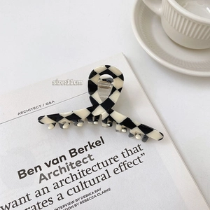 Detail of 11cm checkerboard hair claw clip next to a coffee cup and white magazine