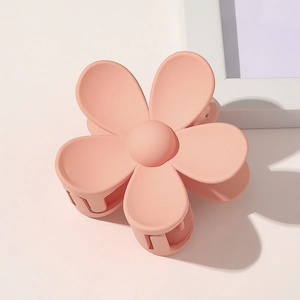 Detail of a matte peach pink flower hair claw clip with frosted texture and spring design