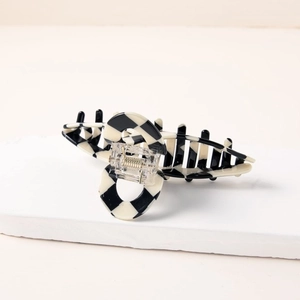 Detail of checkered hair claw clip with strong metal spring on marble surface