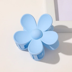 Close-up of light blue matte flower hair claw clip with spring on minimalist background