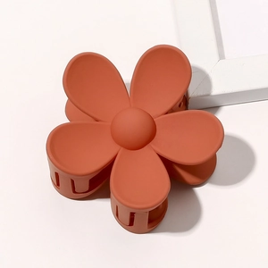 Macro detail of a high-quality matte orange flower hair claw clip on white background