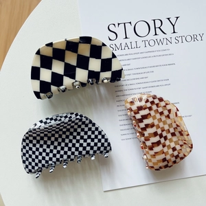 Elegant shell-shaped checkered acetate hair claws in black, white, and brown patterns