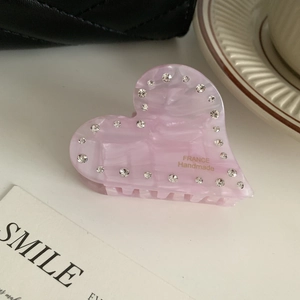 Dettaglio di una molletta per capelli a cuore rosa marmorizzato con strass scintillanti