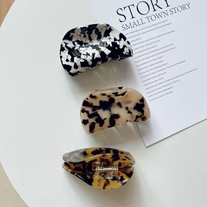 Three acetate hair claws in marble and tortoiseshell patterns with metal spring detail