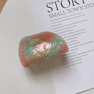 Detailed view of a marble texture acetate shell hair claw with pink and green swirls