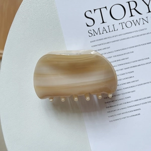 Macro view of shell-shaped cellulose acetate hair claw with marble texture finish