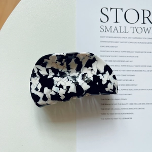 Detailed view of black and white marble acetate hair claw clip on minimalist background
