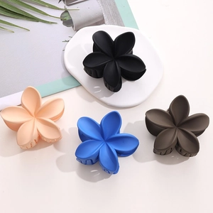 Pinces à cheveux fleurs mates en quatre couleurs sur un plateau moderne en céramique