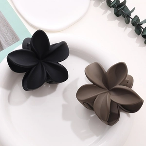 Pinces à cheveux fleurs mates noires et marron café sur une assiette blanche décorée