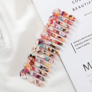 Close-up of colorful marble pattern acetate comb with vintage wavy edges on satin fabric