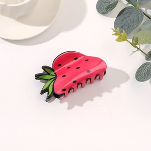 Dettaglio di un fermaglio per capelli lucido a forma di fragola su sfondo bianco