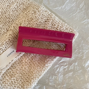 Detail view of pink acetate hair claw with France Handmade text on knit fabric