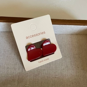 Gros plan de boucles d'oreilles cœur rouge foncé en résine sur carte faite main