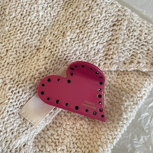 Detail of pink acetate heart hair claw clip with black dots on a beige knit texture
