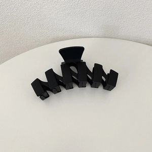 Detail shot of a large matte black hair claw clip with a unique geometric zigzag design