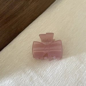 Vue détaillée d'une pince à cheveux nœud rose-violet mat sur un fond en tissu texturé