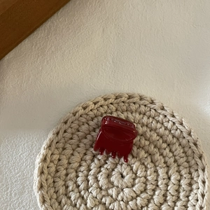 Détail de la petite pince à cheveux rouge brillante sur un support tressé minimaliste