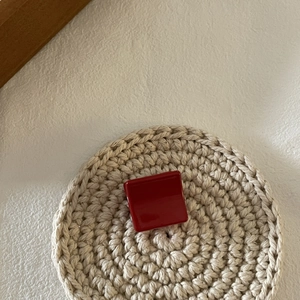 Gros plan d'une pince à cheveux carrée rouge brillant sur un fond minimaliste chic