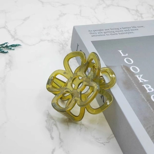 Detailed macro shot of an olive green flower hair claw clip with marble texture on props