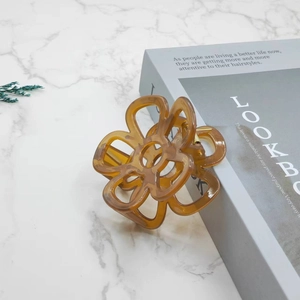 Detailed view of hollow flower claw clip in translucent amber resin on marble surface