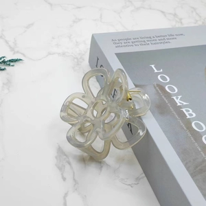 Detail of flower hair claw with marble texture and metallic logo on marble background