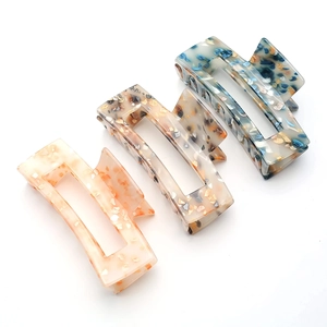 Close-up of three square marble-textured acetate hair claws in pastel pink, beige and blue