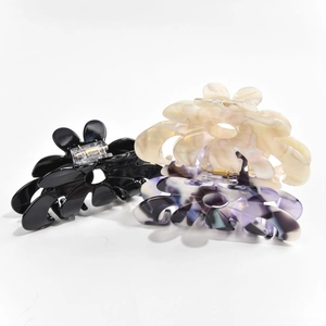 Close-up of floral acetate claw clips in black, white marble, and purple shades
