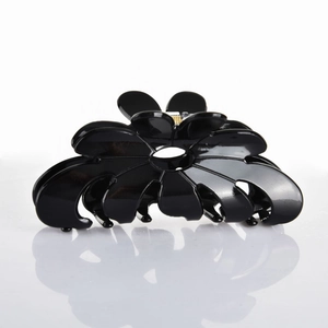 Macro view of black flower acetate hair claw clip with glossy finish and metal spring