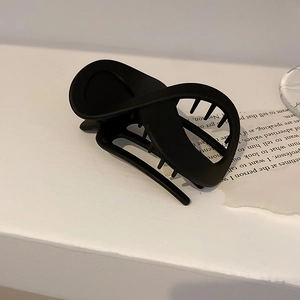 Nahaufnahme einer mattschwarzen Haarklammer mit minimalistischem Dreh-Design auf Papier