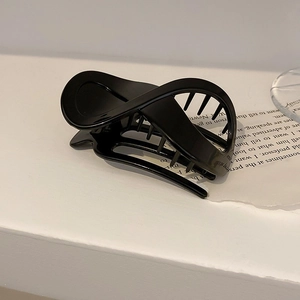 Glänzende schwarze Haarklammer mit Kreuzdrehung auf minimalistischem Hintergrund