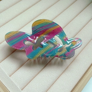 Détail d'une pince à cheveux papillon arc-en-ciel en acrylique sur un plateau à bijoux
