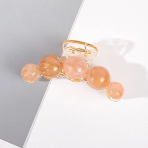 Détail d'une grande pince à cheveux orange pêche translucide avec ressort doré et perles