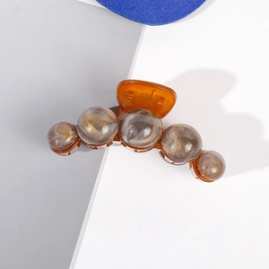 Détail d'une grande pince à cheveux ambre transparente avec des perles effet marbré