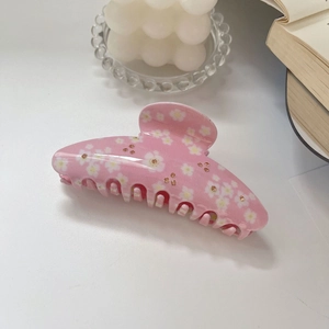 Detailansicht der rosa Gänseblümchen-Haarklammer mit Strasssteinen auf einem Buch