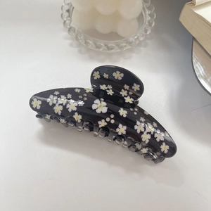 Detail einer schwarzen Acetat-Haarklammer mit weißen Gänseblümchen und Glitzersteinen