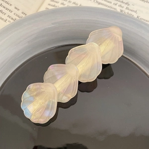 Détail de pinces à cheveux en forme de coquillage en acétate avec fini nacré